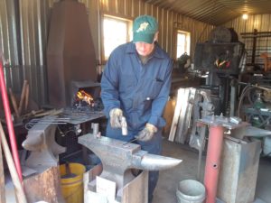 photo of Dale Burton, artisan blacksmith, hammering some steel at his anvil