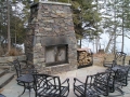 Outdoor fireplace featuring custom forged doors and wood rack